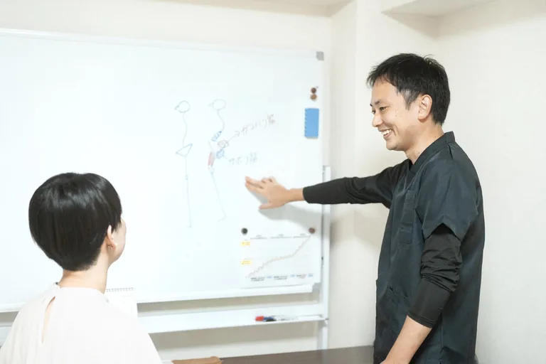 ホワイトボードを使って体の状態と施術方針を説明している様子