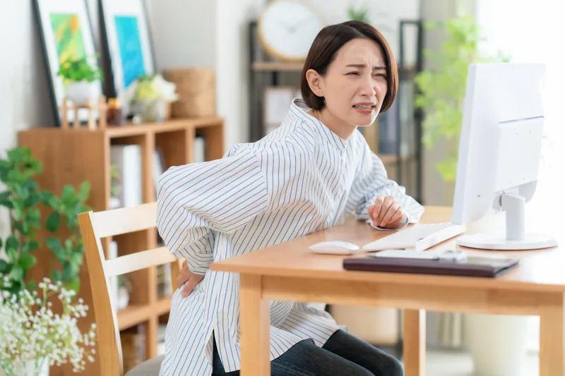 デスクワーク中に腰痛を感じる女性