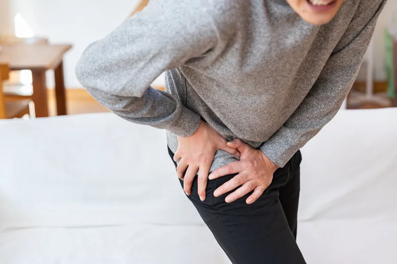 股関節に手を当てて痛みを感じる男性