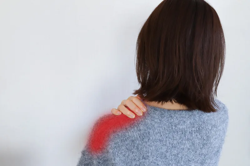 肩の痛みに悩む後ろ姿の女性